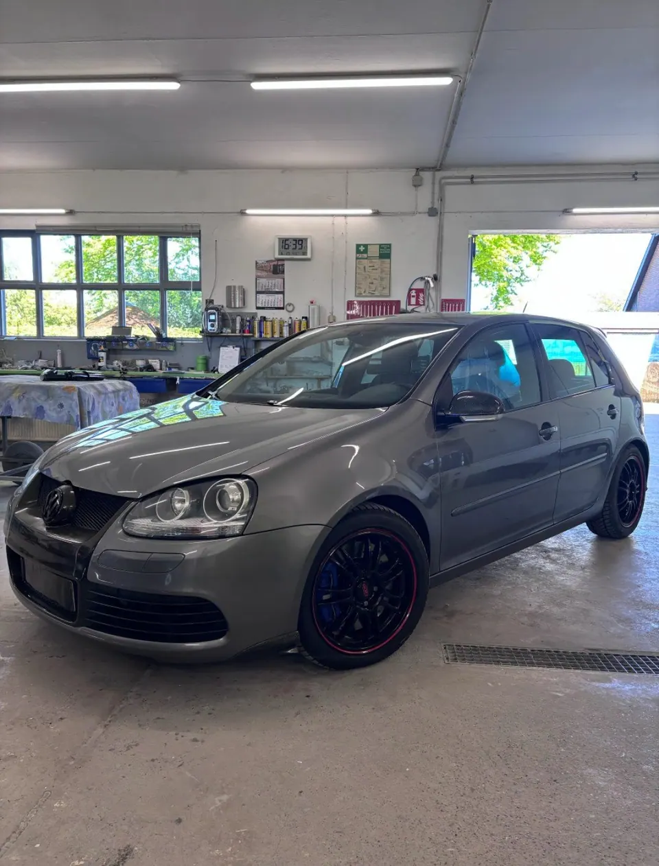 Grauer VW Golf GTI mit schwarzen Felgen und rotem Felgenrand in der Werkstatt