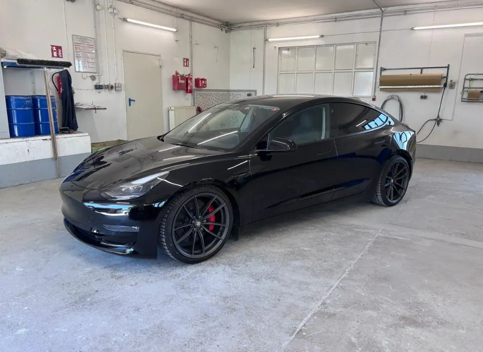 Schwarzer Tesla Model 3 mit Hochglanzlack und roten Bremssätteln in der Werkstatt